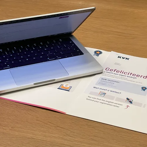 A MacBook and the KvK registration document on a clean desk